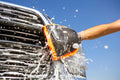 A person using the Extend-A-Reach orange chenille microfiber mitt to wash an RV for scratch-free cleaning