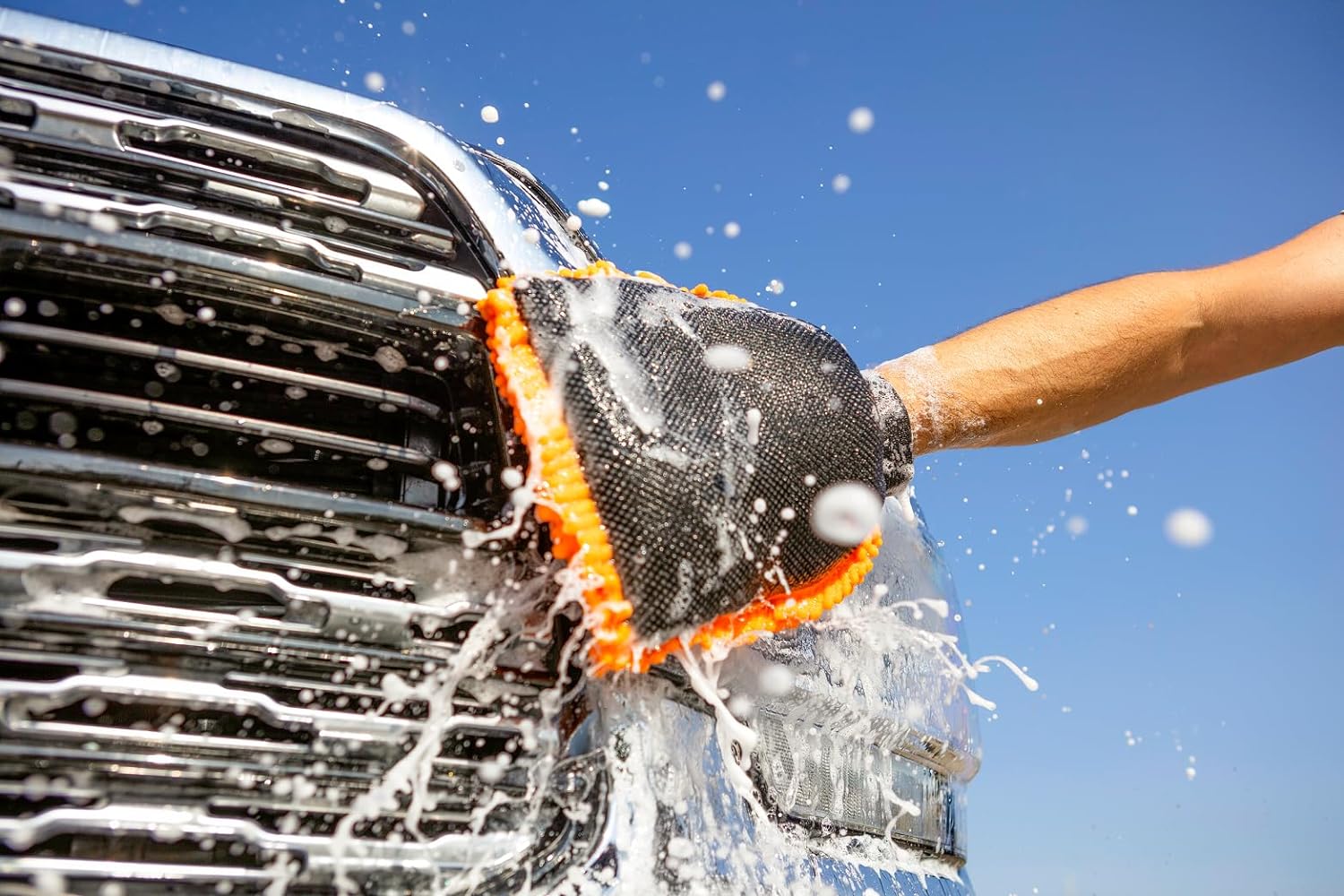 A person using the Extend-A-Reach orange chenille microfiber mitt to wash an RV for scratch-free cleaning