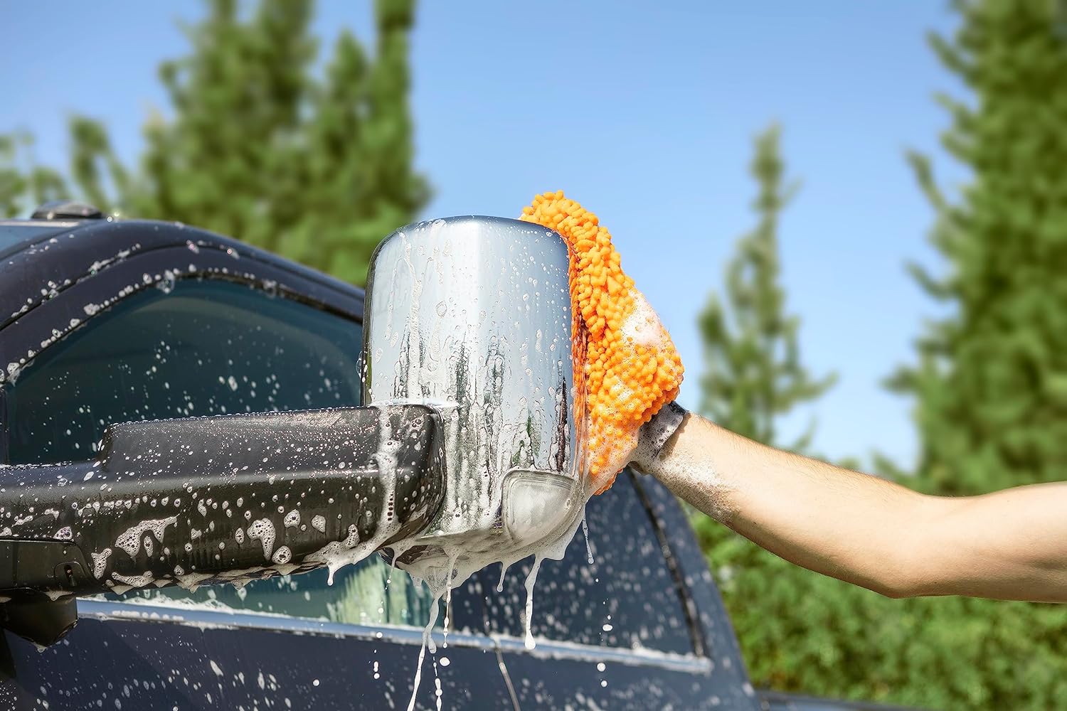A person using the Extend-A-Reach microfiber car wash mitt to wash a truck mirror, providing safe, scratch-free vehicle cleaning