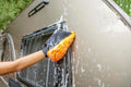 A person using the Extend-A-Reach orange chenille microfiber mitt to wash an RV wall for scratch-free car cleaning