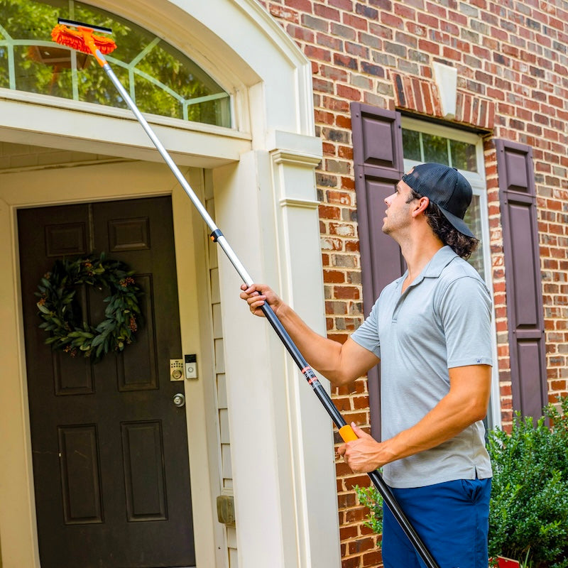 Man using a window cleaning tool on a house exterior