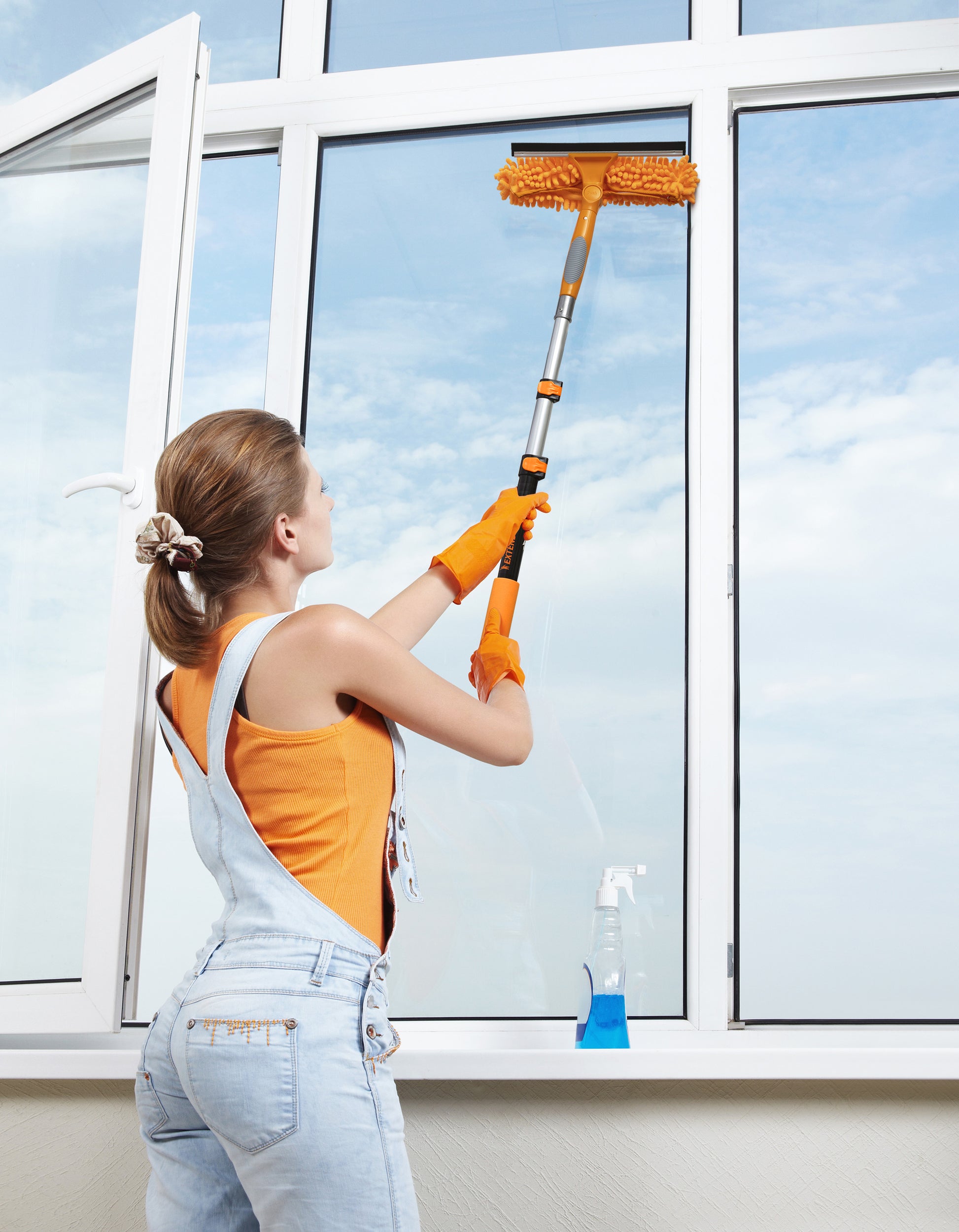 Woman cleaning tall windows with the Extend-A-Reach window washing extension pole, a telescoping pole that attaches to a window squeegee with a universal metal twist for streak-free, high-reach cleaning