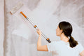 Woman painting a tall wall with Extend-A-Reach painters pole extendable, a telescoping paint pole for ladder-free precision painting